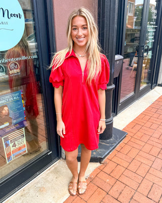 Model wearing a scarlet red puff sleeve quarter-zip dress with a relaxed fit and sporty collar detail.