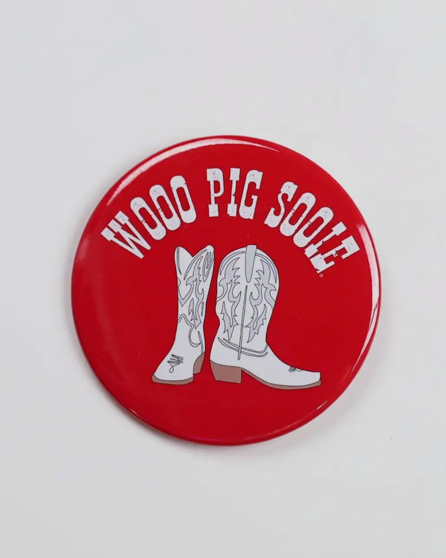 Red button badge  with white cowboy boots and 'Wooo Pig Sooie!' text on a white background