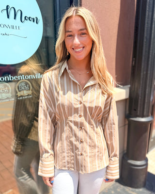Model wearing a tan and ivory striped tailored button-front blouse with a collared neckline, long sleeves, and white denim jeans.