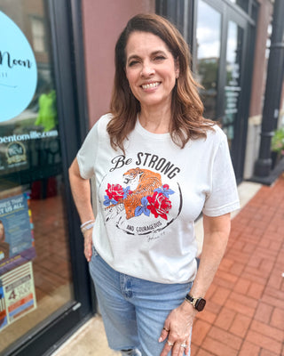Model wearing a vintage white Oat Collective Strong and Courageous Christian graphic t-shirt featuring tiger and floral artwork inspired by Joshua 1:9.