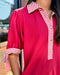 Red shirt with white striped collar and cuffs worn by a person.