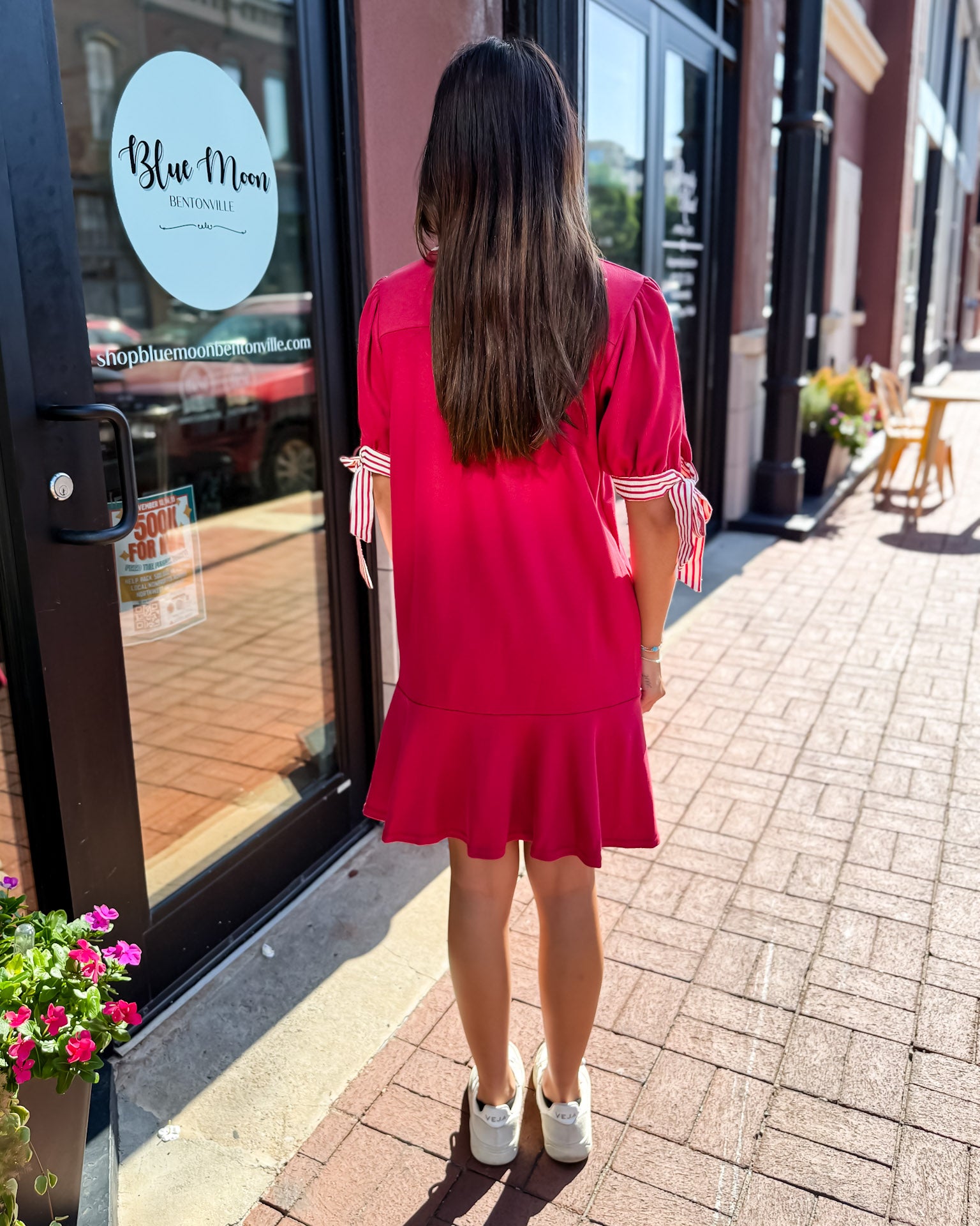 Woman in a red dress standing outside a store with 'Blue Moon' branding.
