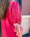 Person wearing a bright pink dress with striped sleeves in an outdoor setting