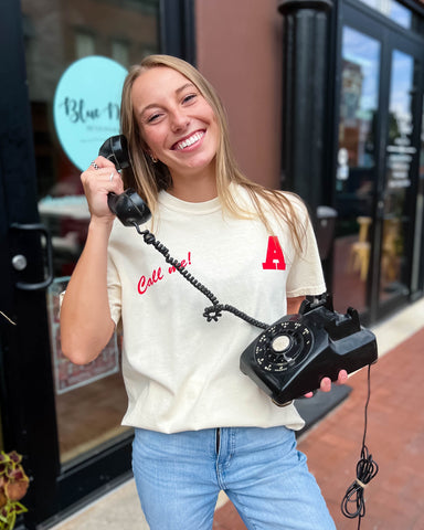 girl wearing cream graphic t-shirt & holding a vintage phone